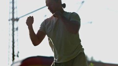 Yetenekli bir dövüşçü, dinamik yumrukları canlı bir günbatımına karşı kullanır ve muazzam enerjisini ve yeteneğini gösterir. Yavaş çekim