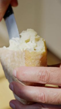 Parlak, davetkar bir ortamda taze bir ekmek parçasına nazikçe yayılan bir elin detaylı bir yakın çekimi. Yüksek kalite 4k görüntü