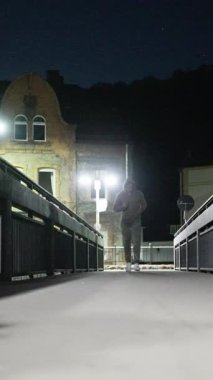 Kararlı bir koşucu gece köprü boyunca koşar, sokak lambalarıyla aydınlatılır, spor ve sükuneti kucaklar. Ağır çekim. Yüksek kalite 4k görüntü