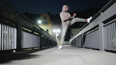 Bu dinamik ortamda, gece boyunca bir köprüde kibarca uzanan ve kentsel zindelik gösteren bir insan. Ağır çekim. Yüksek kalite 4k görüntü