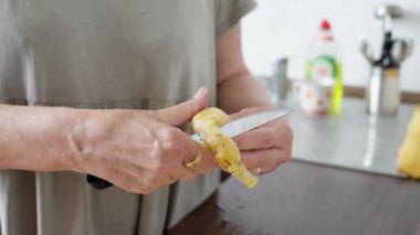 İyi aydınlatılmış, neşeli bir mutfak ortamında patatesleri ustalıkla soyarken, yemek hazırlıklarını ön plana çıkarırken...