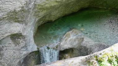 Avusturya. Hermagor. Garnitzenklamm. Doğal bir mağaranın içindeki berrak bir havuza akan sakin bir şelale güzel kaya oluşumları sergiliyor. Yavaş çekim