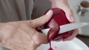 Besleyici yemekler ya da canlı salatalar hazırlamak için taze pancarı ustalıkla ve dikkatle soyan bir insan.