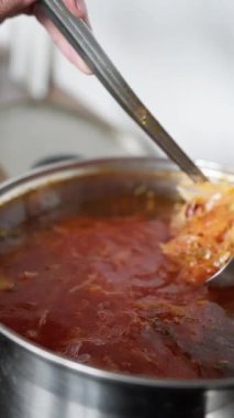 Lezzetli bir çorbanın yakın plan çekimi bir tencerede karıştırılır ve zarif bir şekilde servis edilir, pişirme sürecinin altını çizer.