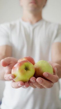 Bir adam gururla elinde canlı, taze elmalar sunar. Hem tazelik hem de sağlıklılığını gösterir.