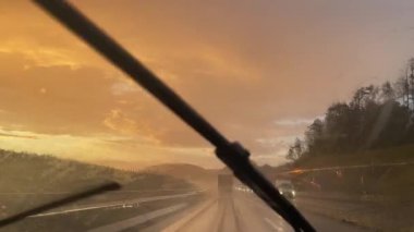 A stunning scene shows a rainy road in sunset hues with tall skyscrapers elegantly in the background. High quality 4k footage