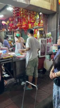 Lezzetli sokak yemekleri ve şenlikli dekorasyonların tadını çıkaran insanlarla dolu hareketli ve canlı bir gece pazarı. Bangkok Tayland 1403 2023.