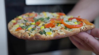 Fırından çeşitli renkli malzemelerle dolu taze pişmiş bir sebze pizzası çıktı. Yüksek kalite 4k görüntü