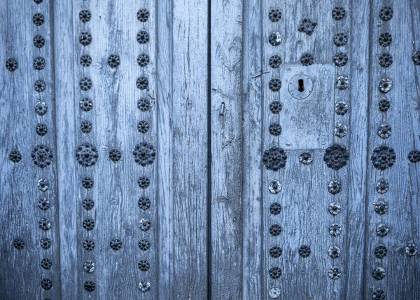 Old aged two-leaf door with metal decorations in natural wood of blue-gray color