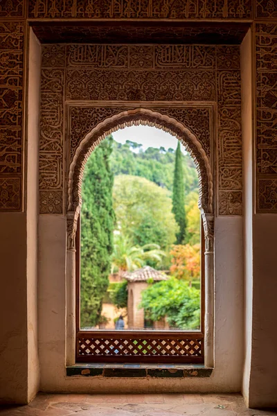 グラナダのアルハンブラ宮殿からのレリーフで飾られた窓 背景にぼやけてカラフルな庭園とスペイン — ストック写真
