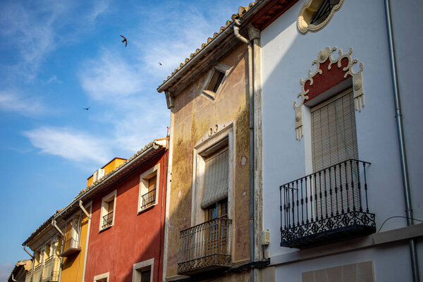 Typical colorful facades of houses in the historic center of Caravaca de la Cruz, in Murcia, Spain, with swallows flying in the blue sky
