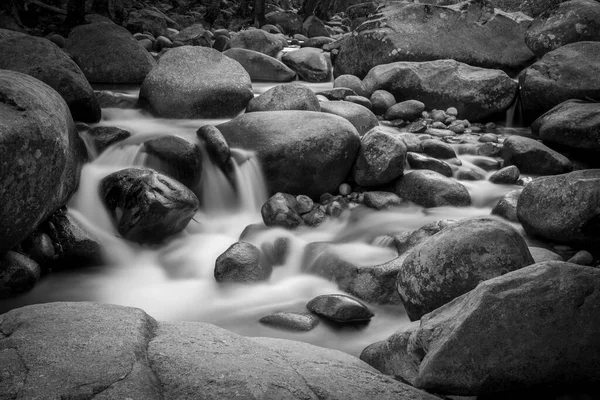 stock image River with rounded rocks photographed with long exposure in black and white