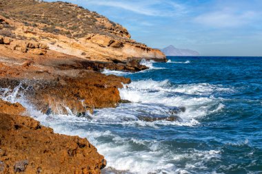 Rugged, rocky coast with surf in Cabo Cope and Puntas de Calnegre Regional Park, Murcia, Spain, in daylight clipart