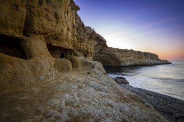 Sunrise view of Cala Blanca in the Puntas de Calnegre regional park in the Region of Murcia, Spain with its typical cave houses clipart