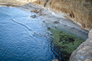 İspanya 'nın Murcia bölgesindeki Puntas de Calnegre bölge parkının Cala Blanca plajından hafif dalgalar ve kayalar kıyıya vurur.