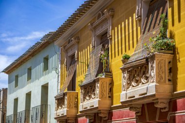 İspanya 'nın Murcia bölgesindeki Pliego' da öğle vakti ışıklarıyla süslenmiş renkli malikane ve balkon yüzleri.