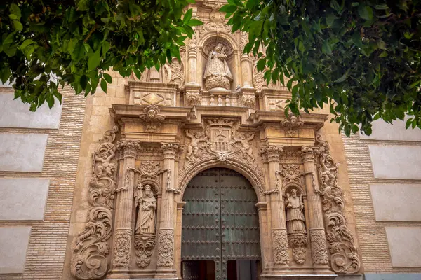İspanya, Murcia 'daki La Merced kilisesinin iki portakal ağacı arasındaki süslü ve barok cephesinin ayrıntıları.