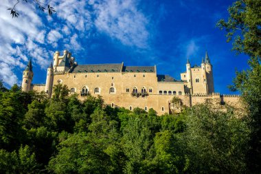 Paseo del Eresma 'dan Segovia, Castilla y Leon' un kuzey cephesinin manzarası, kalın ağaçları ve yoğun mavi gökyüzü.