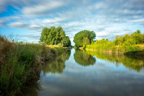 stock image Beautiful landscape of the Castilla canal with riverside trees on its sides and the sky reflected in its calm waters. As it passes through Fromista, Palencia, Spain