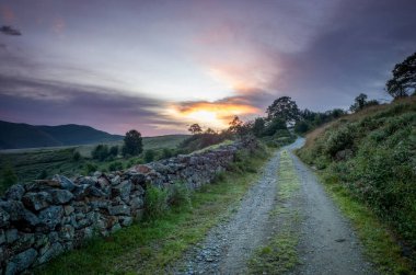 Bucolic rural road in the mountains of the Saja Besaya natural park in Cantanbria, Spain, at dawn in summer clipart