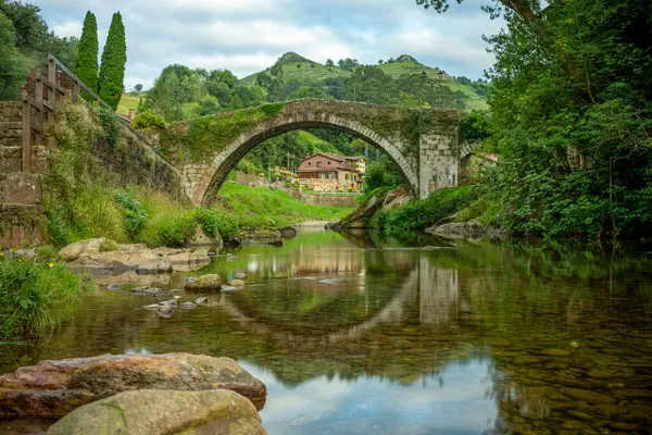 Miera nehri üzerindeki yarı dairesel kemer köprüsü, Lirganes, Cantabria, İspanya, sularındaki yansımasıyla