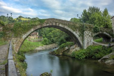 Miera Nehri üzerindeki yarı dairesel kemer köprüsü, Lirganes, Cantabria, İspanya, yan taraftan görüldü.