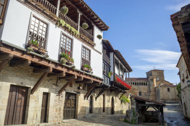 Santillana del Mar kasabasındaki tipik ortaçağ caddesi, Cantabria, İspanya, tarihi bir şehir ve arka planda üniversite kilisesi ile tarihi-sanatsal kompleks ilan edildi.