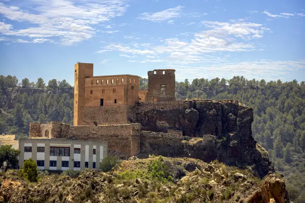 Cofrentes Şatosu, Valencia, İspanya. Şehrin hemen üstündeki tepede bulutlu mavi gökyüzü var.
