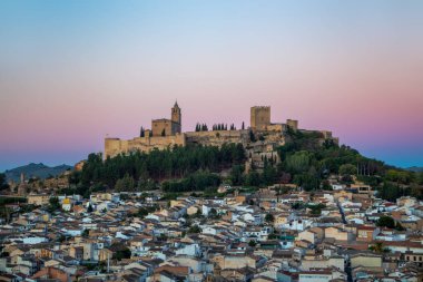 Alcal la Real 'deki La Mota Kalesi, Jan, Endülüs, İspanya, pembe gündoğumu ışığı ve aşağıdaki kasaba