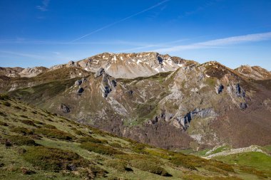 İspanya 'nın Asturias kentindeki Somiedo Doğal Parkı' nın panoramik manzarası, baharın ortasında tepeden muhteşem bir manzara, vadilerde kar ve vadilerde çimenler.