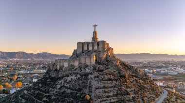 Gün batımında arka planda meyve bahçesiyle birlikte etkileyici Monteagudo Kalesi 'nin panoramik manzarası Murcia, İspanya