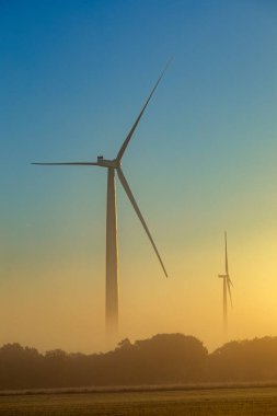 İspanya 'nın La Mancha kentindeki renkli gündoğumunda iki rüzgar türbininin dikey görüntüsü