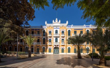 Eski topçu kışlalarından birinin güneşli cephesi Murcia, İspanya 'daki kendine özgü sarı renginde binalar.