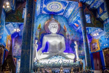 Beyaz Buda sunakta, Mavi Tapınağın içinde, Chiang Rai, Tayland 'da, yapay ışıklandırmalı.