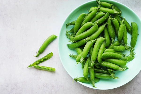 stock image Green pea pods in the plate top view. Summer vegetable crop