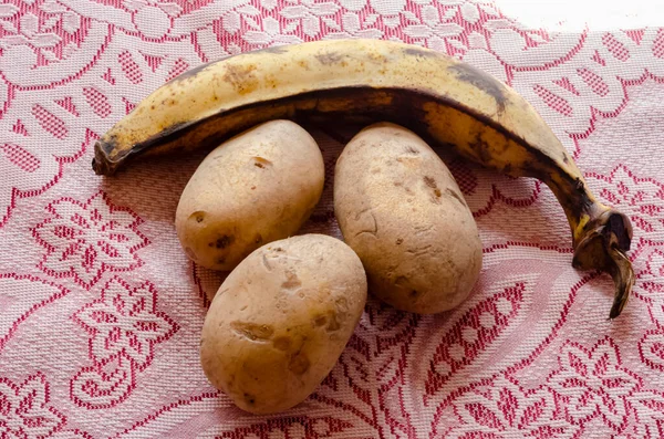 Ein Reifer Kochbananen Und Drei Weiße Kartoffeln Stehen Auf Einer — Stockfoto