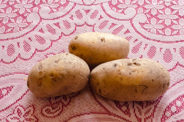 三个爱尔兰土豆铺在红白花边桌布上 — 图库照片
