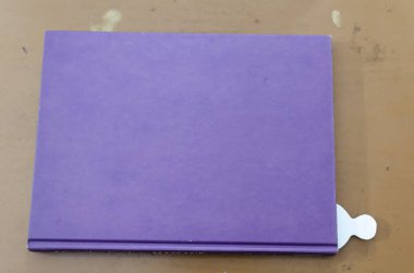 Yan tarafında beyaz bir işaret olan kapalı bir kitap kahverengi bir masanın üzerinde duruyor..