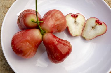 Four whole and two halves royal apples are in a white plate clipart