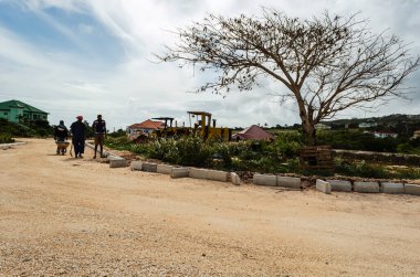 İşçiler beton bloklara doğru ilerliyorlar. Bu bloklar mermer bir yolun kenarındaki kavşağın etrafından geçecekler..