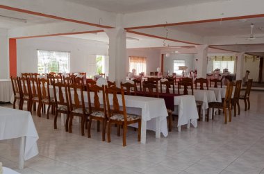 Hepsi yemek odasında beyaz masa örtüsü ve ahşap sandalyelerle kaplı masalarda yatıyor..