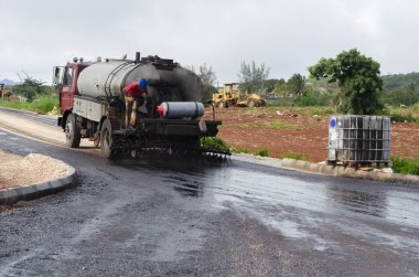 Yuvarlak tanklı bir kamyon yeni bir yol boyunca petrol dağıtıyor..