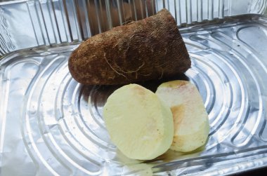 Peeled and un-pealed yam tuber are inside of an aluminum pan.