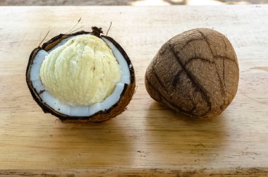 A broken coconut has an embryo that grows to fill the endosperm and a whole endosperm are on a table. clipart