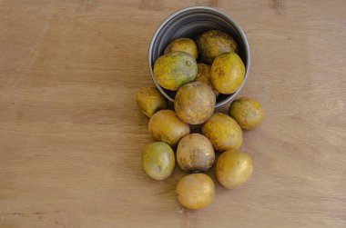 Bir tahta yüzeyinde çizgili kahverengi bir tabak var. Üstünde de haziran erikleri var..