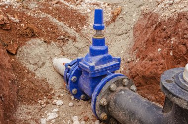 Yeni yapılmış mavi bir yangın musluğu beyaz kireç taşı, kaya, mermer ve terra rossa kil toprağıyla çevrilidir..