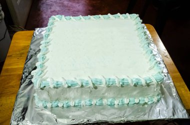 Buzlu meyveli kek küçük bir ahşap masanın üzerinde..