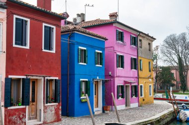 Burano, Italya- 25 Şubat 2023; Burano İtalya 'da bir kanal boyunca renkli evler