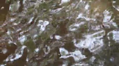 Soyut derin su sahnesi, damlayan ve akan su görüntüsü, ayrıntılı olarak parlak su dalgaları. Hareket eden su yüzeyinin makro görünümü 