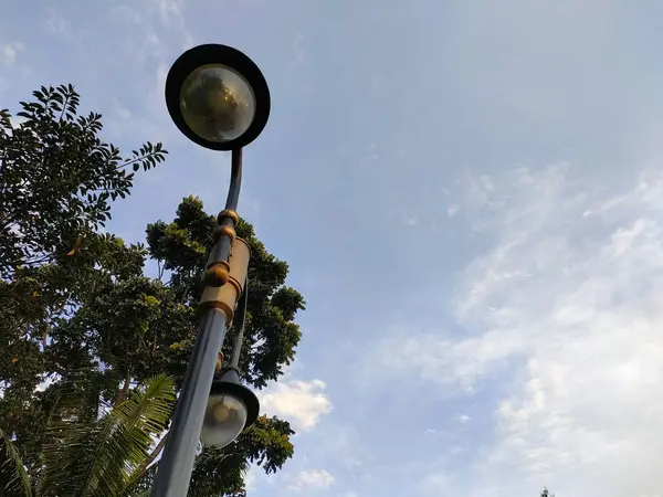 Parçalı bulutlu gökyüzüne karşı çift yuvarlak ışıklı uzun sokak lambası. Kentsel, altyapı, temalı görsel içerik için ideal